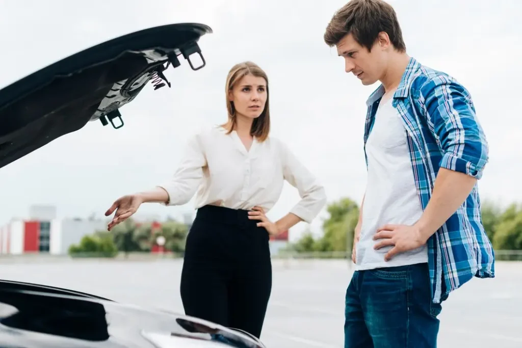 Man and woman discussing vehicle issues with open car hood, reflecting concerns about accident-related vehicle maintenance in Greenway Parks.